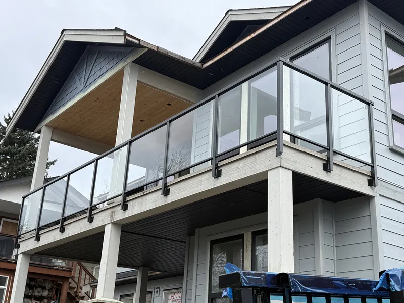 Clear glass railing wrapping a second-storey deck under a gabled roof