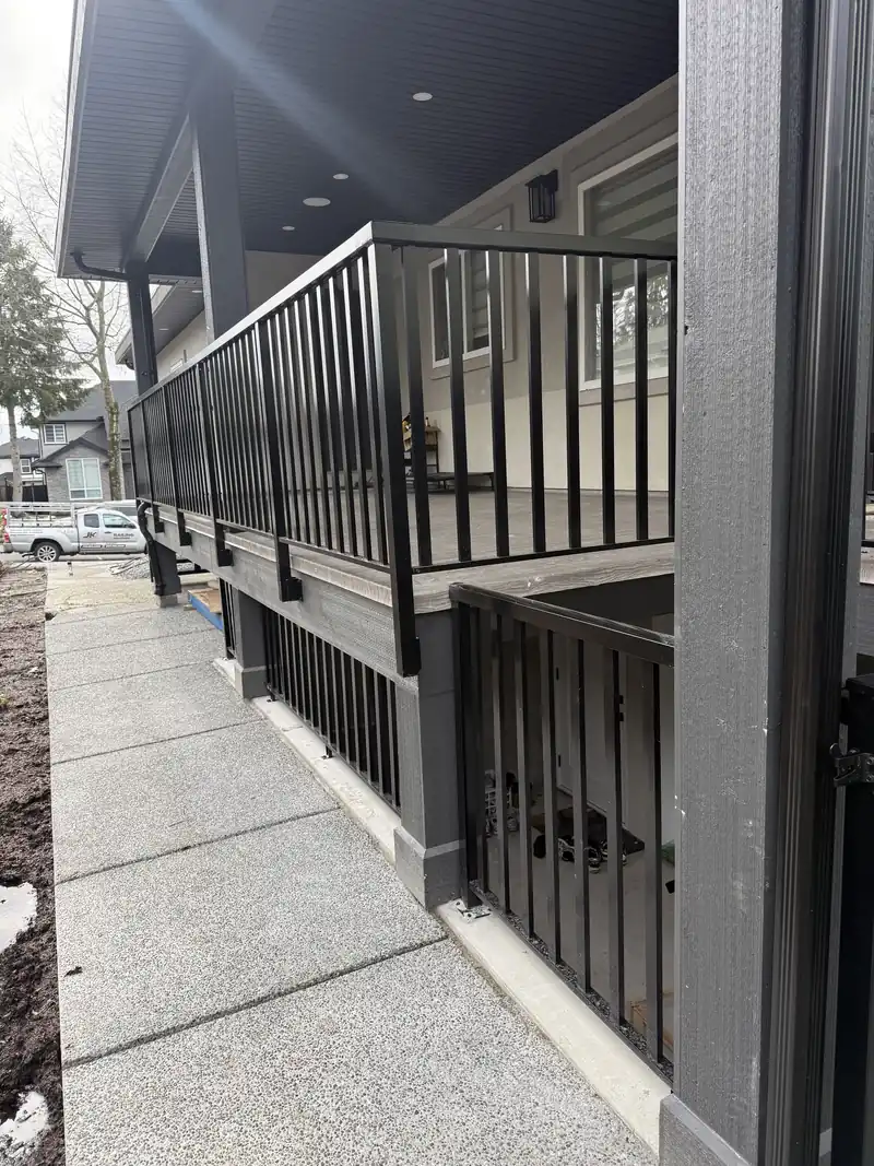 Wide-picket black aluminum railing along a covered deck