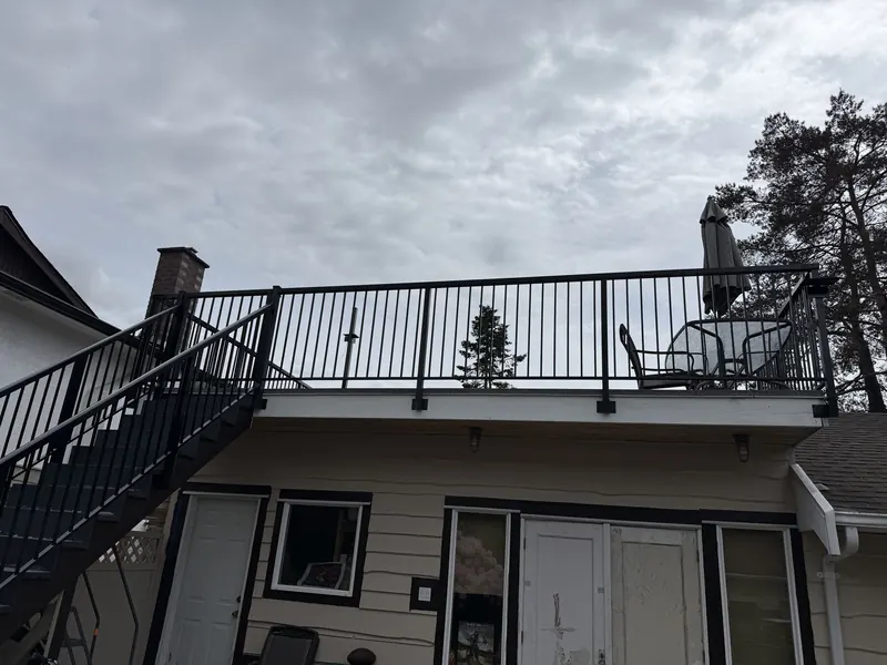 Picket railing around a garage roof deck with an aluminum stair