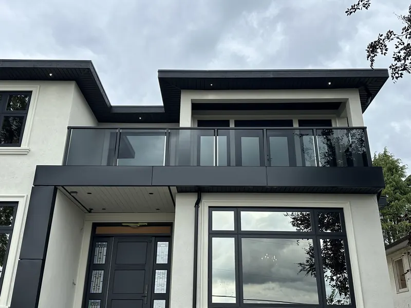 Smoked glass railing in a black frame across a modern second-floor balcony